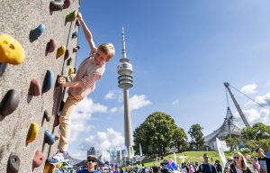 Das Foto zeigt einen Jungen, der eine Sportkletterwand erklimmt.