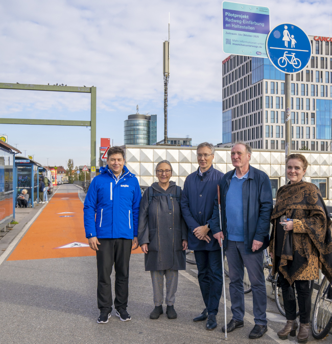 Das Foto zeigt fünf Personen neben einem Buswartehäuschen auf der Donnersbergerbrücke. Der Abschnitt des gemeinsamen Geh- und Radwegs neben dem Buswartehäuschen ist orange eingefärbt. Die fünf Personen sind von links nach rechts: Christopher Utz, MVG-Betriebsleiter Bus, Karola Klein, Vorsitzende des Fachausschusses „Öffentlicher Raum“ des Seniorenbeirats, Mobilitätsreferent Georg Dunkel, Bernhard Claus, Vorsitzender des Facharbeitskreises Mobilität im Behindertenbeirat, und Baureferentin Dr.-Ing. Jeanne-Marie Ehbauer. Foto: LHM, DobnerAngermann