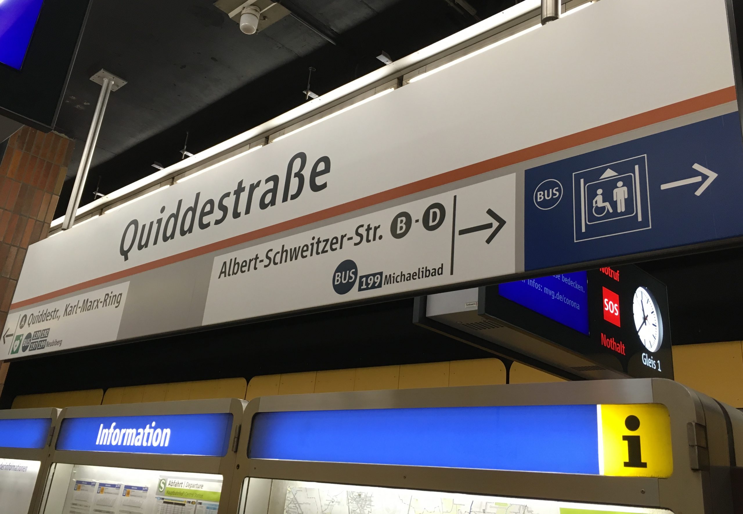 Hinweisschild in der U-Bahn-Station Quiddestraße mit großem Aufzug-Piktogramm und Bus-Symbol